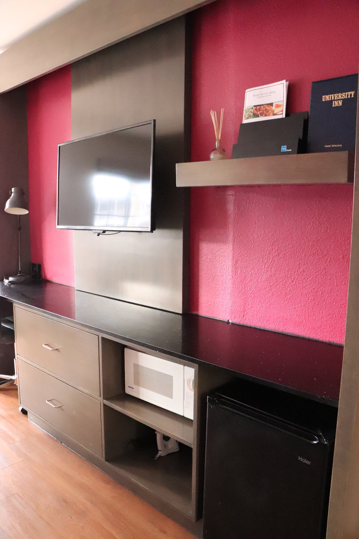 3 Bed Family Room — TV wall unit with microwave, mini-fridge, and University Inn guest directory
