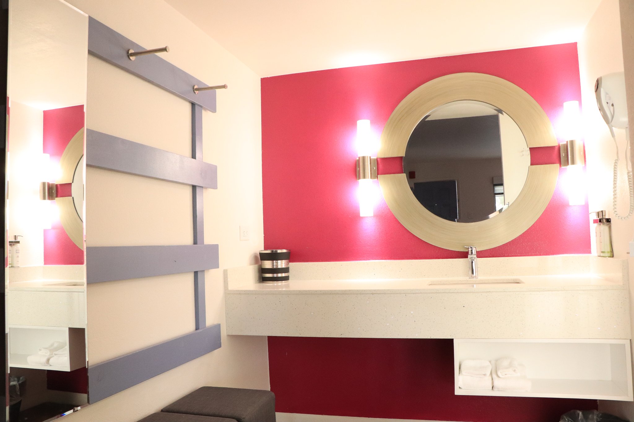3 Bed Family Room — vanity area with round mirror, sconce lighting, and red accent wall